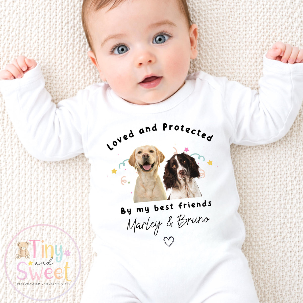 May include: White baby bodysuit with long sleeves, featuring the text "Loved and Protected By my best friends Marley & Bruno". The design includes illustrations of a yellow Labrador and a brown and white Springer Spaniel.